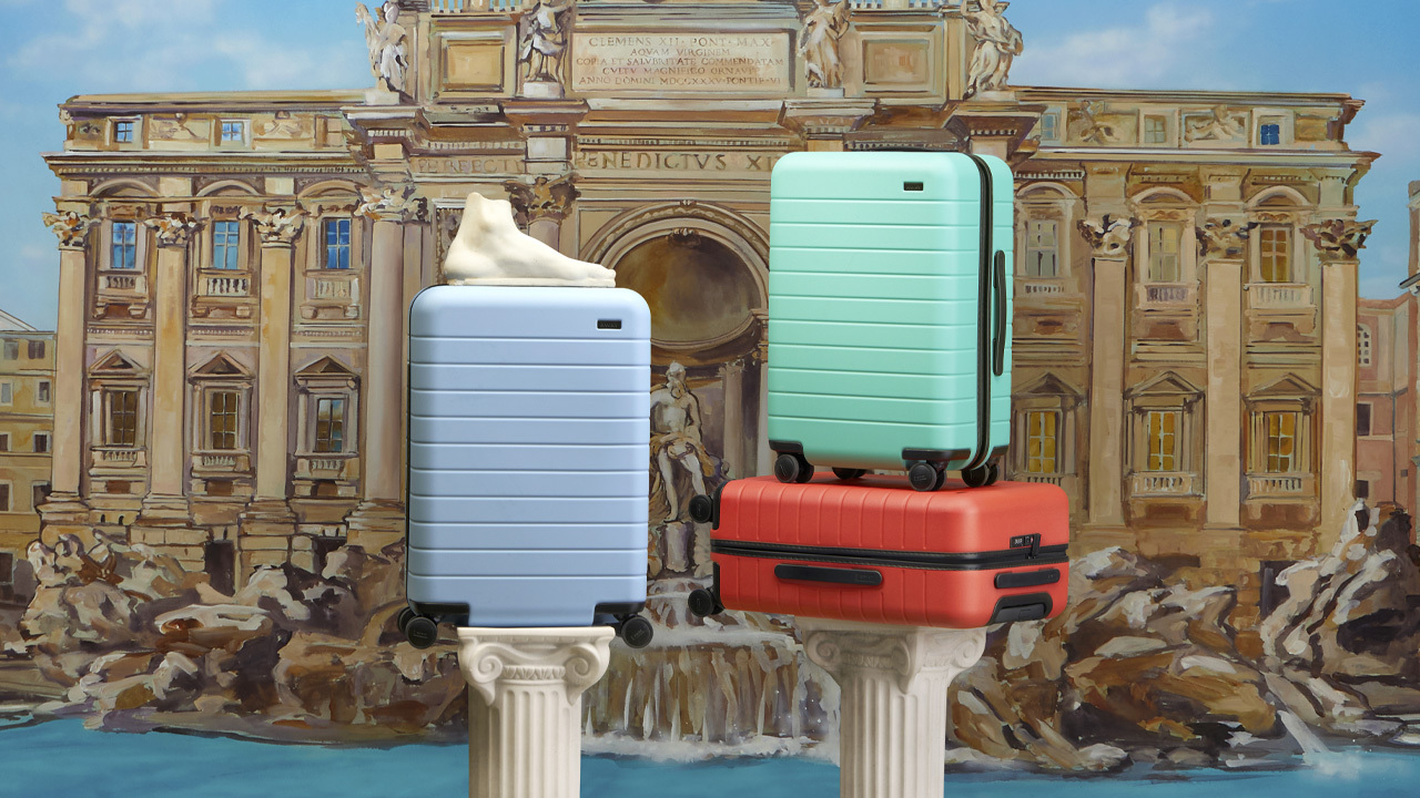 serena williams away collection: Three suitcases from the Away x Serena Williams collection are posed in front of a drawing of the Trevi Fountain in Rome